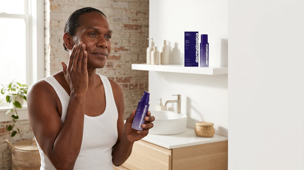 Person with deep brown skin applying an exosome leave-on treatment in a bright minimal bathroom, morning light