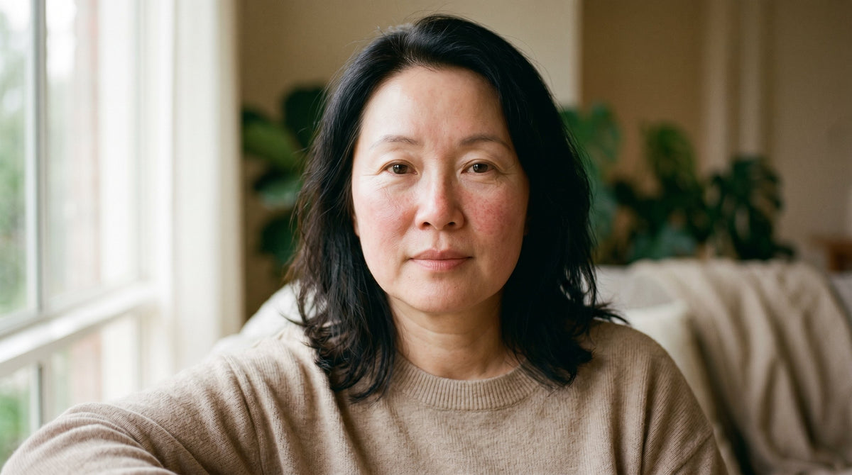 53-year-old East Asian Australian woman with fair skin showing subtle redness across cheeks, photographed in soft natural light with a calm expression